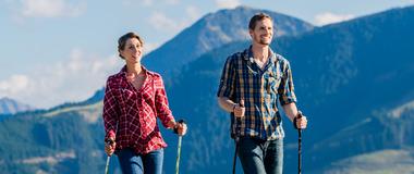 Couple doing Nordic walking exercise in mountains with alpine panorama